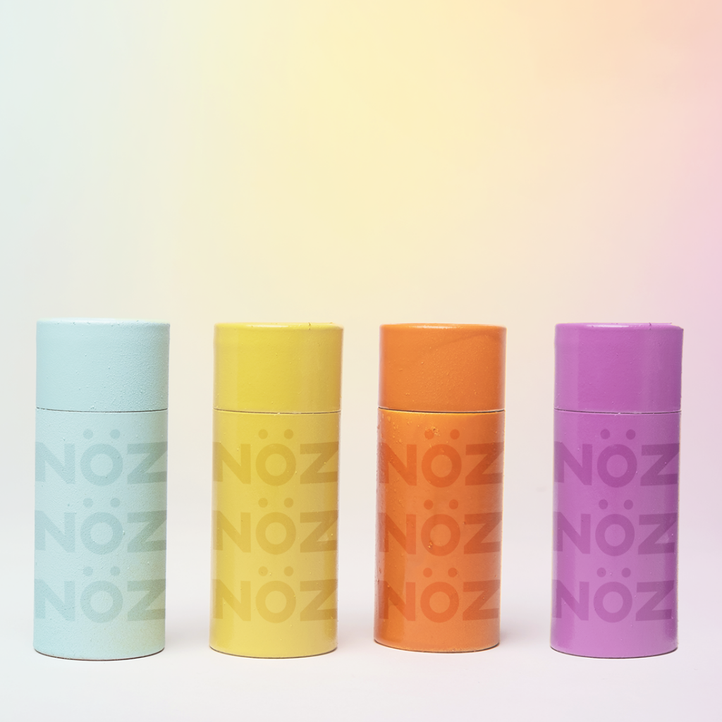 All four colors of Noz sunscreen lined up next to each other in front of a gradient background